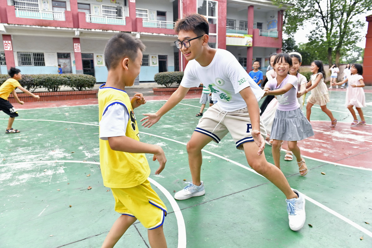 在江西省南昌市湾里管理局罗亭镇义坪小学，大学生志愿者和留守儿童一起做游戏（7月19日摄）。